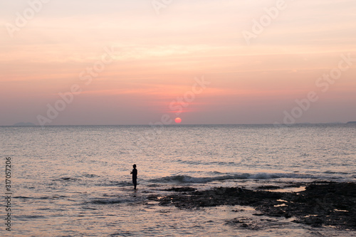 Fisherman in the hat on sea pink sunset background. © anya babii