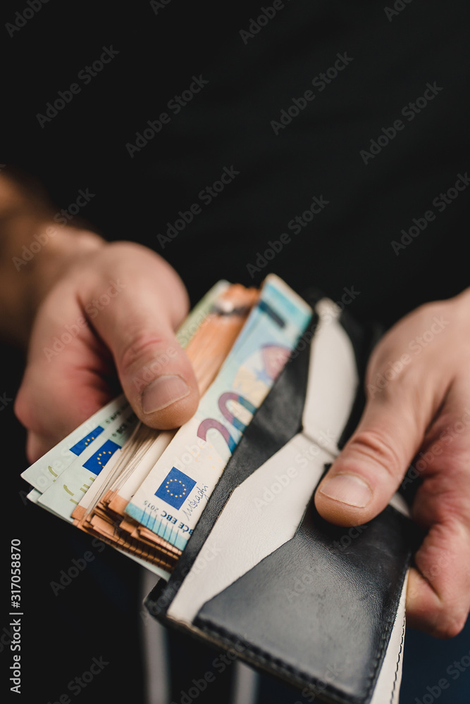 Cash payment - A man takes out euro bills from his wallet Cash payment - A man takes out euro bills from his wallet