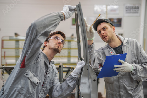 An employee of the quality Department of the car body paint shop provides training on quality control.