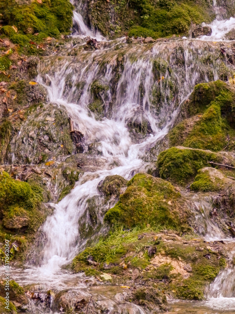 wild landscape with a small waterfall, running water in orange tones. rocks, rocky trees, twigs and moss. wild landscape with a small waterfall, running water in orange tones. rocks, rocky trees, twigs and moss.