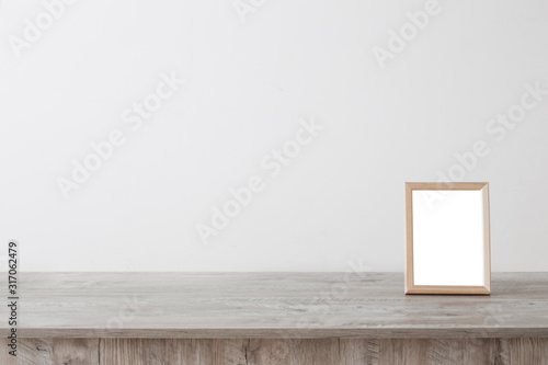 wooden frame on wooden table on background white wall