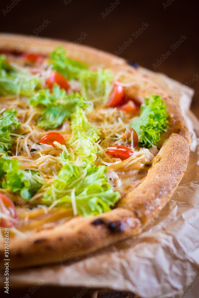 Caesar pizza, with cherry tomatoes, lettuce, Parmesan cheese, crispy crust on a brown background. Caesar pizza, with cherry tomatoes, lettuce, Parmesan cheese, crispy crust on a brown background.