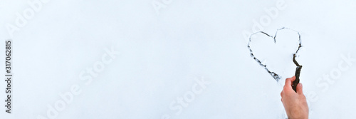 Heart drawn by stick on white snow . Beautiful winter background for Valentines Day or Christmas with copyspace. Stock photo.