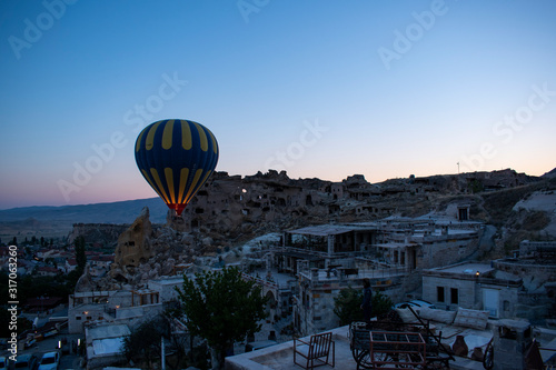 Cappadocia, Turkey: a hot air balloon floating at dawn on the church of St. John the Baptist (Cavusin castle), famous 5th century cave church on top of the hill of the old town of Cavusin 