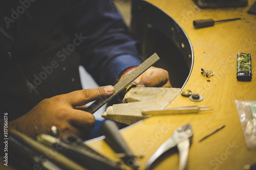 Close up image of a jeweler making jewelery with traditional hand tools in a jewelery shop. photo