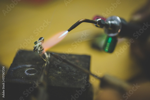 Close up image of a jeweler making jewelery with traditional hand tools in a jewelery shop. photo