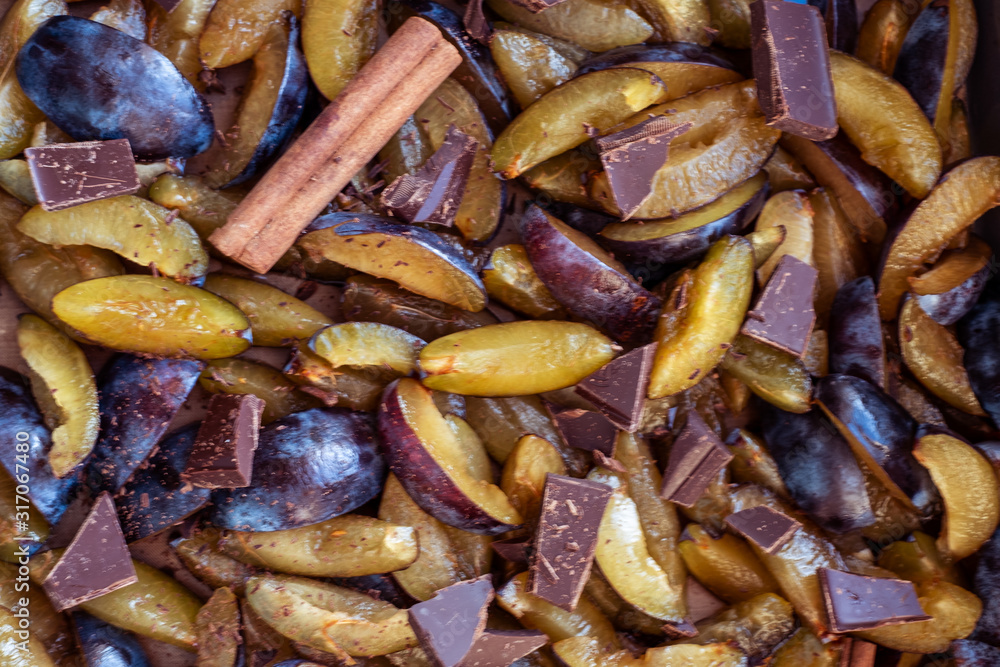 Fresh plum fruit cut into slices, slices with cinnamon sticks, chocolate, cloves. Preparation of ingredients and fruits for making delicious jam. Fresh plum fruit cut into slices, slices with cinnamon sticks, chocolate, cloves. Preparation of ingredients and fruits for making delicious jam.