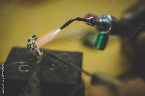 Close up image of a jeweler making jewelery with traditional hand tools in a jewelery shop. photo