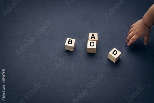 Wooden alphabet cube with words ABCD closeup and children hands on black background. Selective focus and education concept photo