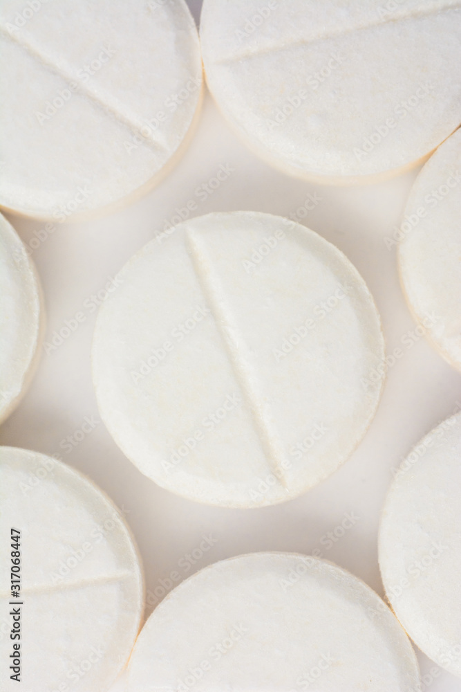 White pills with a line in the middle on a white background, texture of pills. White pills with a line in the middle on a white background, texture of pills.