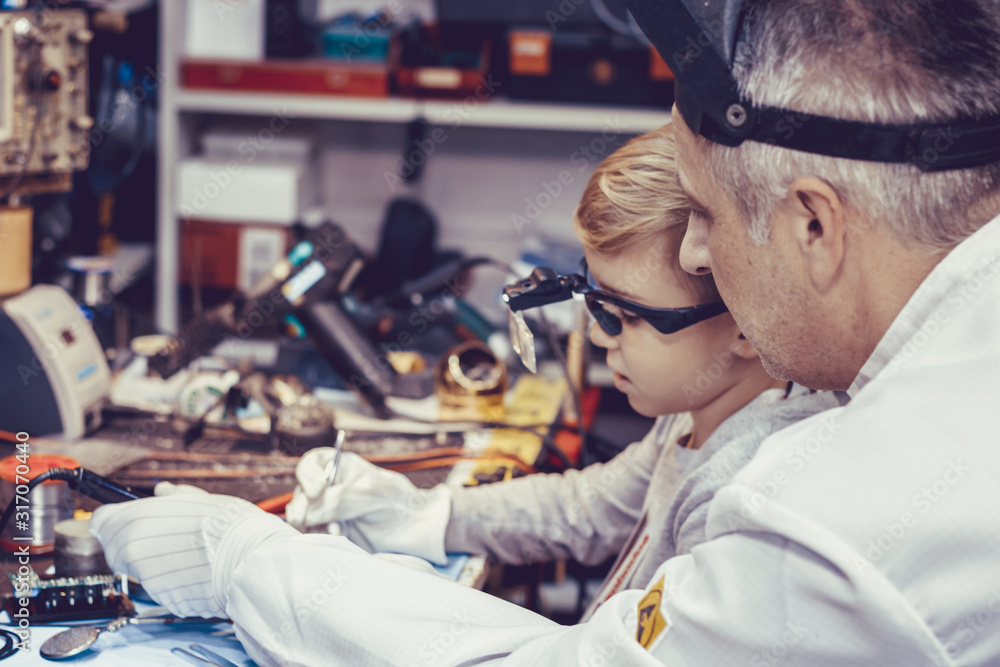 Engineering teacher and small boy repairing computer part in a lab. Engineering teacher and small boy repairing computer part in a lab.