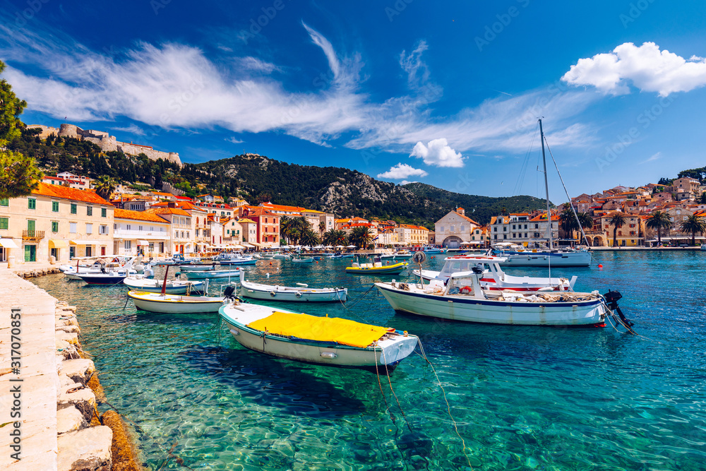 Fototapeta premium View at amazing archipelago with boats in front of town Hvar, Croatia. Harbor of old Adriatic island town Hvar. Popular touristic destination of Croatia. Amazing Hvar city on Hvar island, Croatia.
