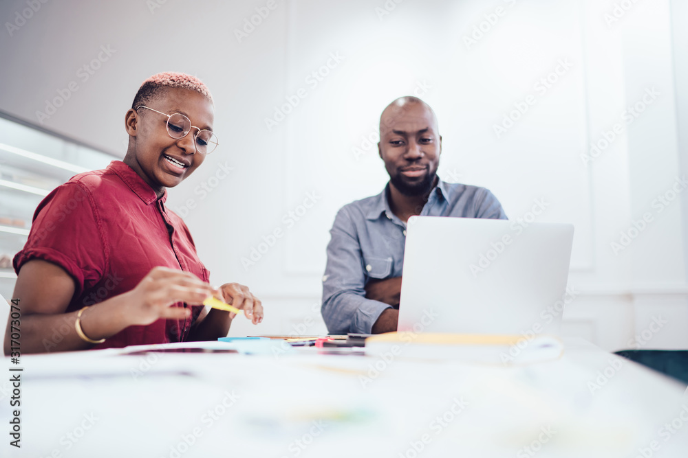Black optimistic freelancer explaining plan of project to coworker Black optimistic freelancer explaining plan of project to coworker