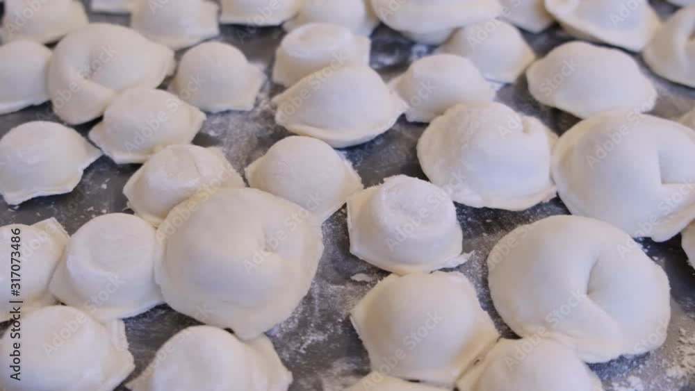 Uncooked Dumplings, Pelmeni lie on a table with flour Uncooked Dumplings, Pelmeni lie on a table with flour
