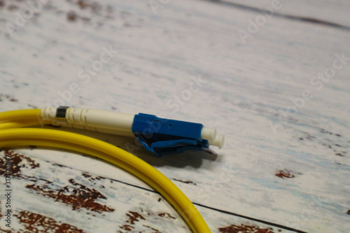 closeup of yellow optical fiber network cable on wooden table background