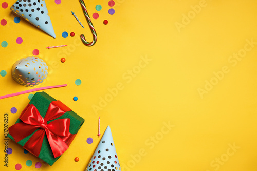 Birthday yellow background with party caps gifts confetti candy copy space