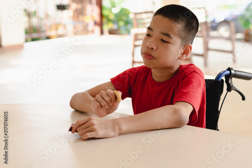 Asian disabled child on wheelchair eating snacks by themselves,The skills to practice muscle development,Special children's lifestyle,Life in the education age,Happy disability kid concept.