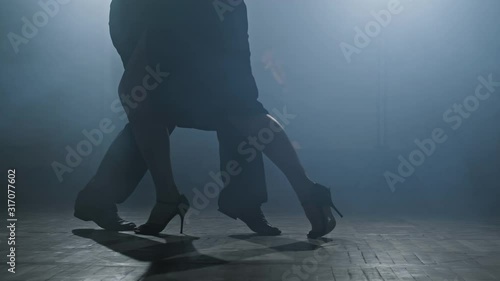 Beautiful man and woman dancing latin dance. Close-up of legs dancing tango in smoky studio in slow motion. 4K, UHD photo