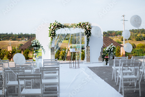 Wedding arc with white flowers at the background of the trees