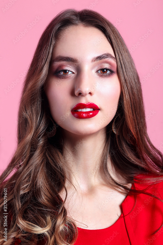 Beautiful face of young woman with red lipstick and curly hair. Portrait of a stunning sexy girl looks at camera. Beautiful face of young woman with red lipstick and curly hair. Portrait of a stunning sexy girl looks at camera.