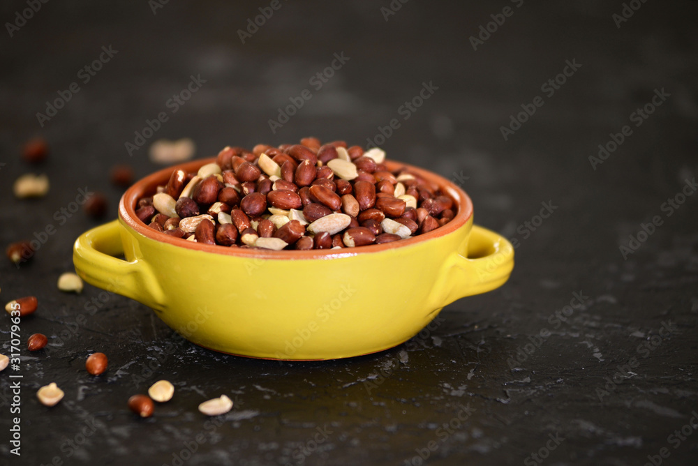 Yellow bowl with peanuts on black texture background. Yellow bowl with peanuts on black texture background.