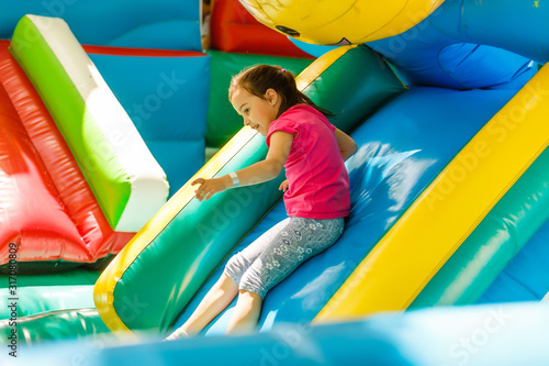 Slika na platnu Little Girl sliding down an inflatable Slide