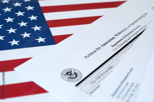 I-360 Petition for Amerasian, Widower or special immigrant blank form lies on United States flag with envelope from Department of Homeland Security