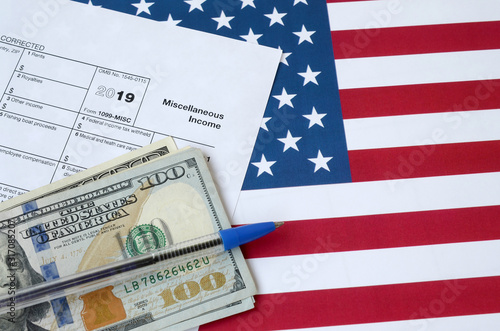 Form 1099-misc Miscellaneous income and blue pen with dollar bills lies on United States flag. Internal revenue service tax form photo