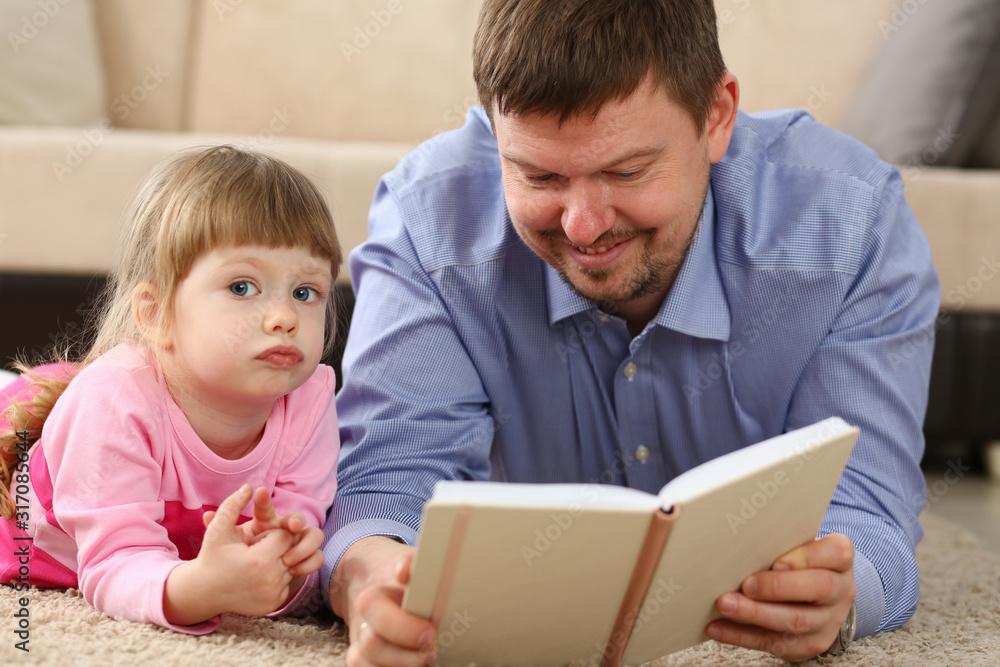 Father and daughter lie on floor reading interesting book together portrait Father and daughter lie on floor reading interesting book together portrait