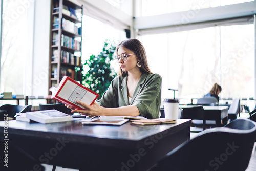 Smart student in glasses reading book