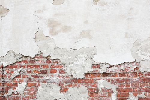 Texture of an old brick wall with fallen plaster. Background of a shabby building surface