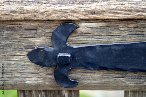 Closeup of a hand-forged barn hinge holding up a wooden garden gate. 