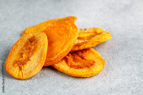 Dried delicious peaches on a gray concrete or stone background. An ingredient for making sweet dishes. Useful fruit. Healthy snack. Selective focus, copy space