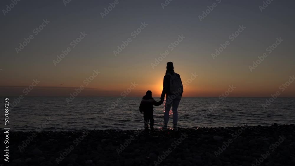 Mom and son enjoy sunset on the coast. Slow-motion video