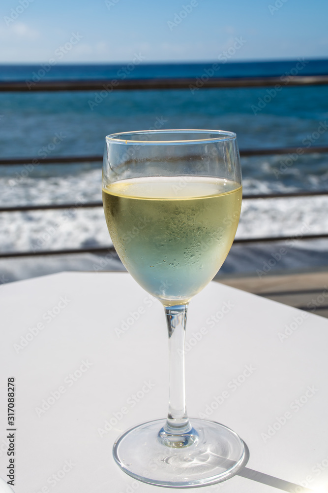 Summer holiday on sea, drinking white wine on outdoor terrace with sea view in sunny day Summer holiday on sea, drinking white wine on outdoor terrace with sea view in sunny day