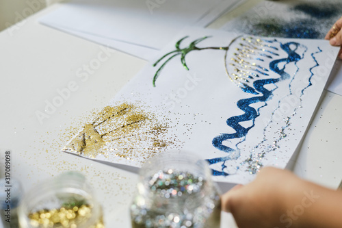 Child's hands shaking off the extra sparkles from the picture