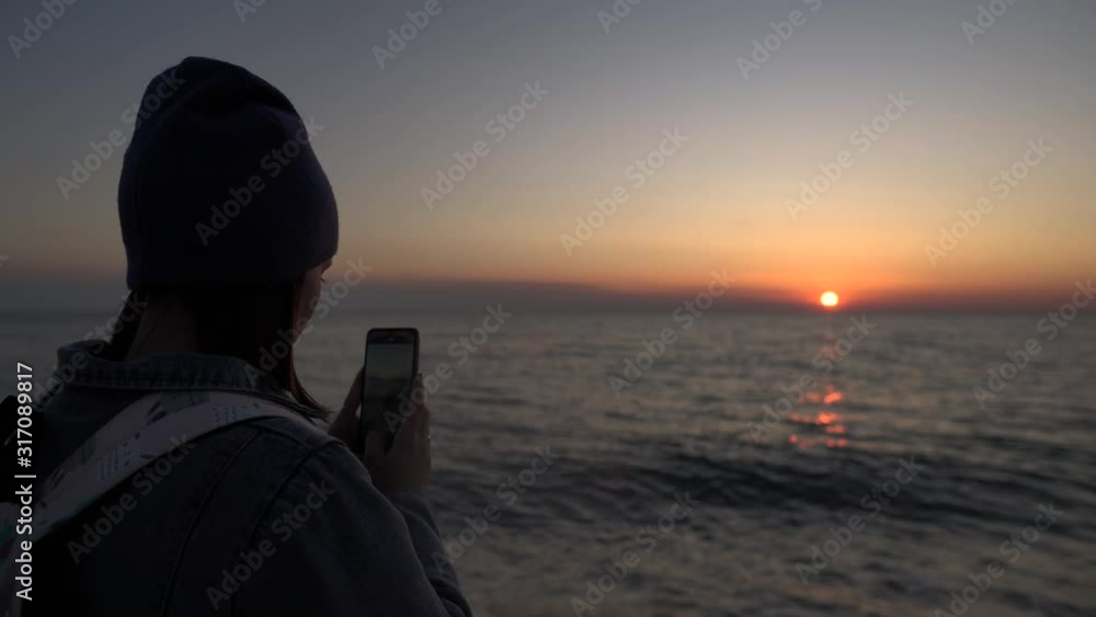 A tourist girl takes pictures on her phone sunset. The silhouette at sunset. A tourist girl takes pictures on her phone sunset. The silhouette at sunset.
