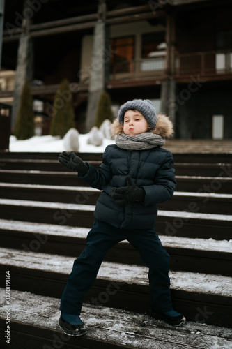 full length shot of cute boy having fun standing on the stairs of the building outdoors