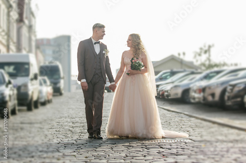happy bride and groom walking on city street. Fototapet