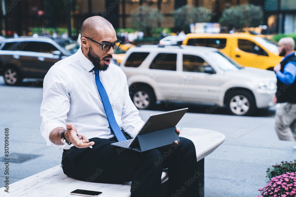 Black surprised entrepreneur looking at tablet screen outside Black surprised entrepreneur looking at tablet screen outside
