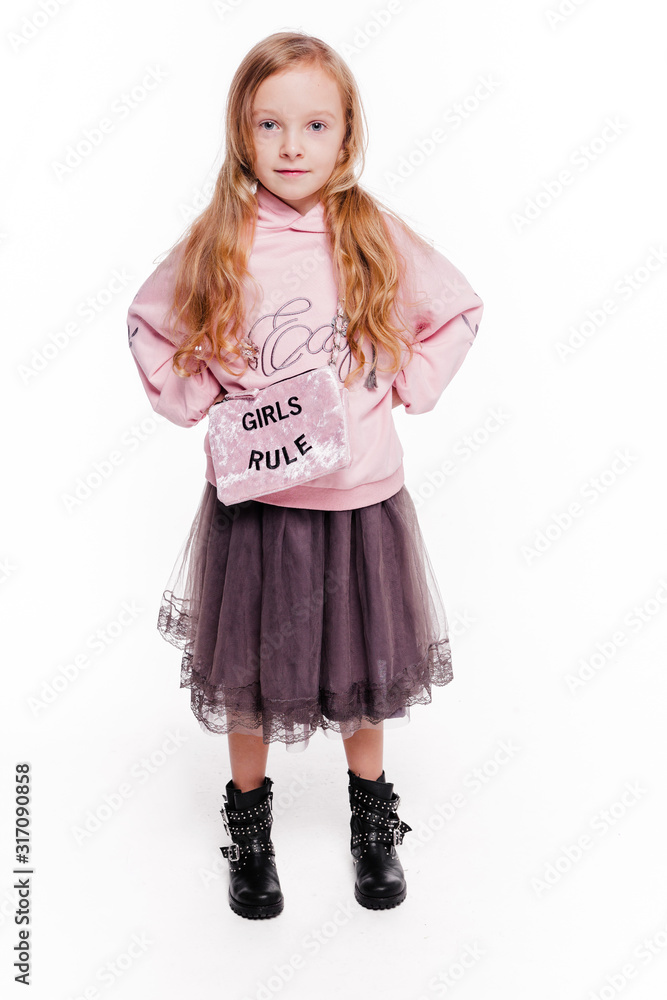 Little fashionable girl in a pink bike with a hood and with a bag with the text rules of the girl. Fight concept Little fashionable girl in a pink bike with a hood and with a bag with the text rules of the girl. Fight concept