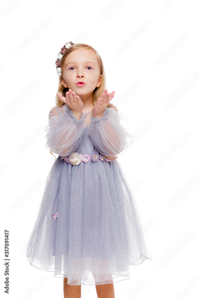Little fashionable red-haired girl in a gray dress with a wreath on her head blows a kiss Little fashionable red-haired girl in a gray dress with a wreath on her head blows a kiss