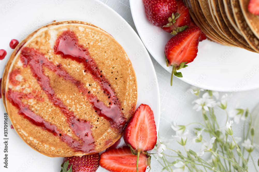 Homemade pancakes with fresh strawberries and honey.