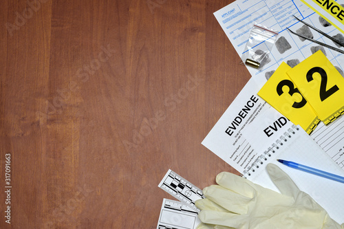Paperwork during crime scene investigation process in csi laboratory. Evidence labels with fingerprint applicant and rubber gloves on vooden table photo