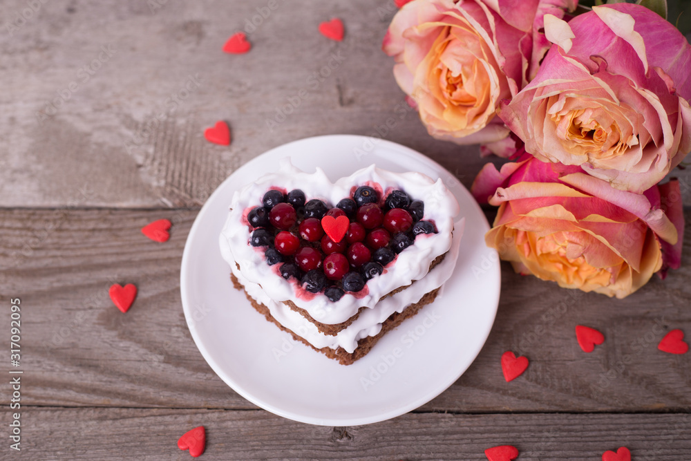 Mini romantic dessert cake for Valentine's Day with roses. Sweet cookies with cream topping and red heart for decor on wooden background. Mini romantic dessert cake for Valentine's Day with roses. Sweet cookies with cream topping and red heart for decor on wooden background.