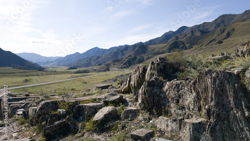 Large boulders and stones against the background of mountains and roads. Travel in the mountains in summer. A trip to the Altai