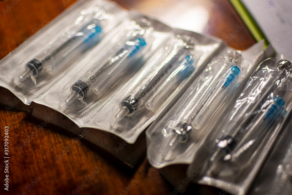New disposable injection syringes in a package, close-up, selective focus. Syringes on a dark wood background. concept of depression, illness. New disposable injection syringes in a package, close-up, selective focus. Syringes on a dark wood background. concept of depression, illness.