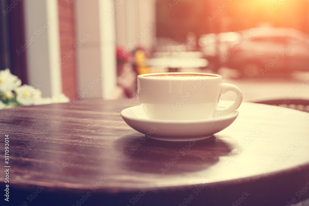 Fototapeta premium View of a summer terrace cafe with cup of cappuccino on the table.