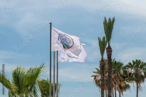 The flag of Agia Napa municipality and the flag of Cyprus. Flags on the flagpole and the stereet lamp post. The wind inflates the flag.