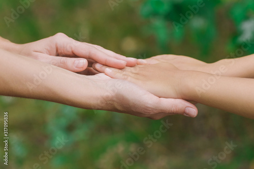 Closeup view of mother and little child holding hands together. Closeup view of female parent and baby. Horizontal color photography. © Andrii Oleksiienko